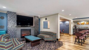 A modern living room with a fireplace, a flat-screen TV, and a seating area with patterned cushions. - Comfort Inn Tulsa Midtown (Tulsa)