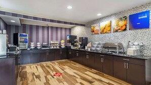 A modern kitchen with dark cabinets, a wooden floor, and a buffet area with various food items and a coffee station. - Comfort Inn Tulsa Midtown (Tulsa)