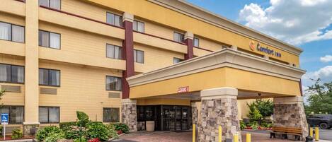 Un hotel Comfort Inn con facciata gialla, ingresso coperto e cartello che indica l'accessibilità per disabili.