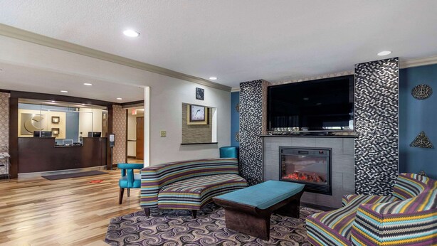 A modern living room with a fireplace, patterned sofas, and a wooden floor. - Comfort Inn Tulsa Midtown (Tulsa)