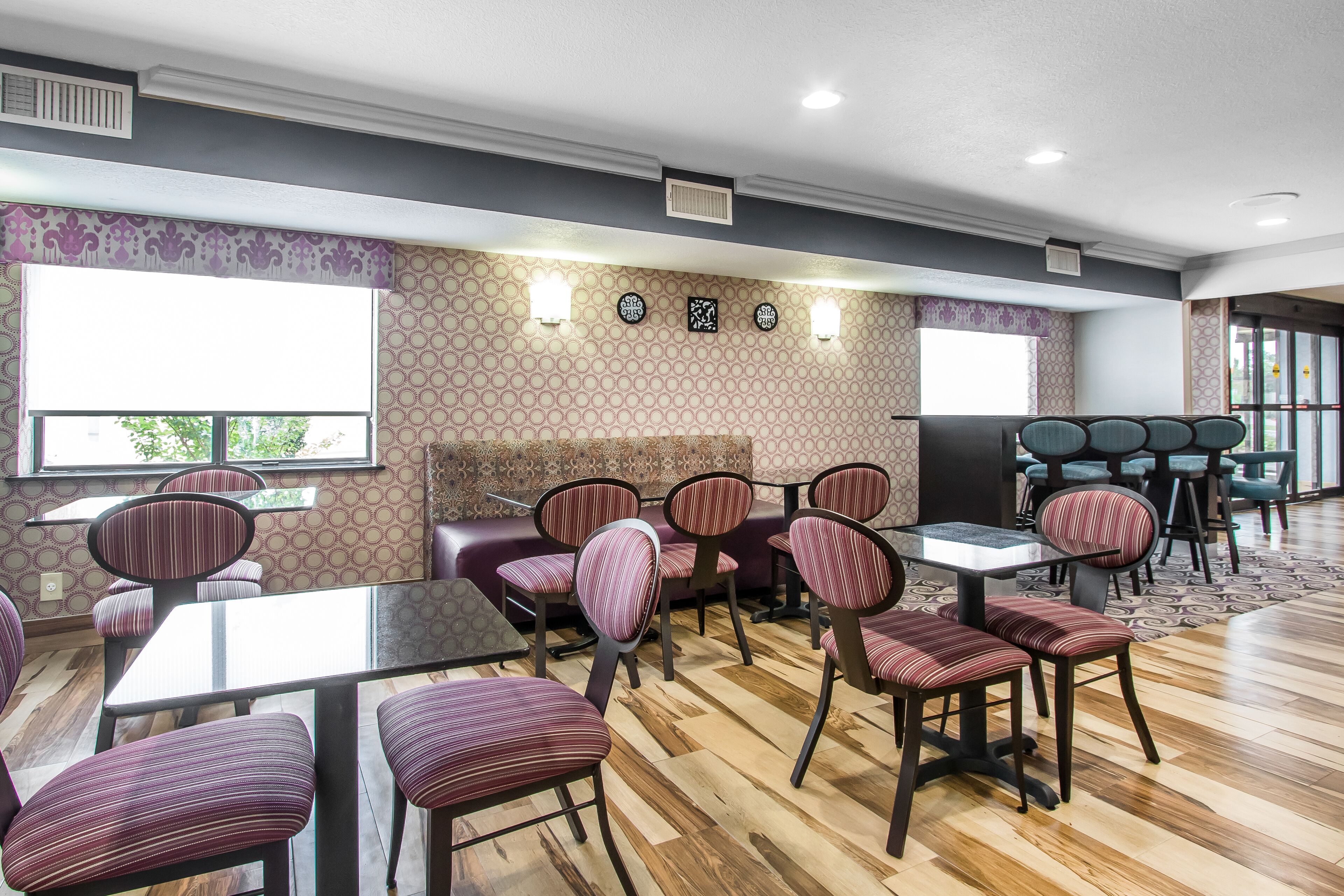 A restaurant with tables and chairs, patterned wallpaper, and a window with a view.