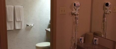 A bathroom with a toilet, a sink, and a hairdryer mounted on the wall.