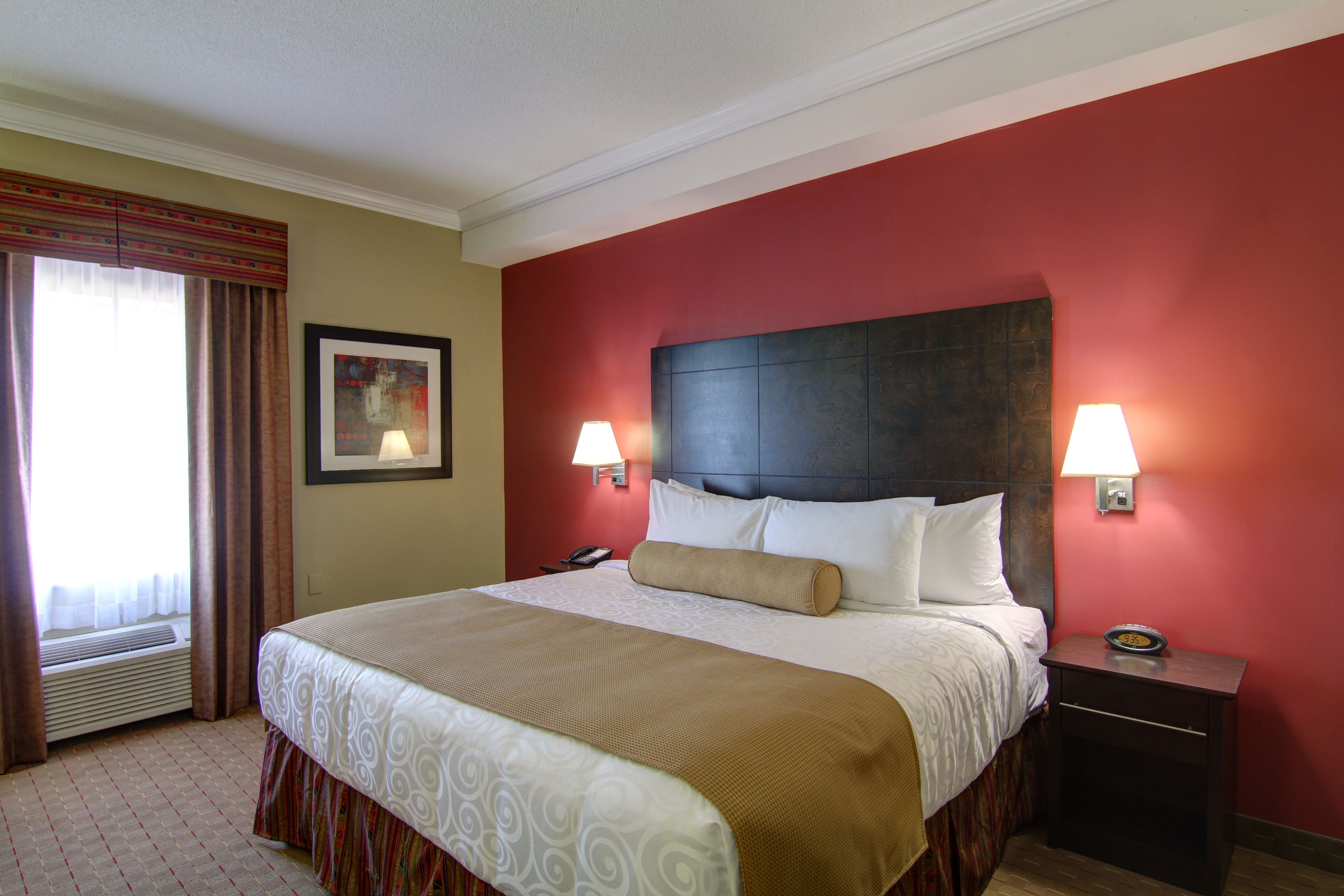 A hotel room with a large bed, two bedside lamps, a nightstand, and a framed picture on the wall.