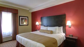 A hotel room with a large bed, two bedside lamps, a nightstand, and a framed picture on the wall.