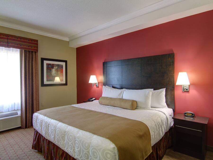 A hotel room with a large bed, two bedside lamps, a nightstand, and a framed picture on the wall.