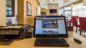 Una reception hotel con un computer, una stampante e una tastiera.