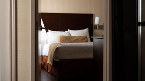 Una camera d'albergo con un letto, un comodino, una lampada e un frigorifero.