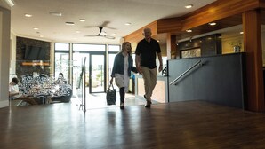 A modern lobby with a wooden floor, a reception desk, and a seating area with a decorative wall. - Inn On Long Lake (Nanaimo)