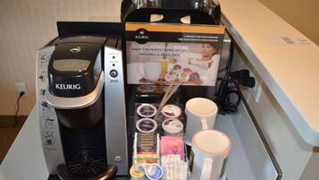 A Keurig coffee machine with a coffee pod holder, a coffee mug, and a box with instructions.