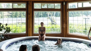 A wooden cabin with a hot tub, large windows, and a view of a lake. - Inn On Long Lake (Nanaimo)
