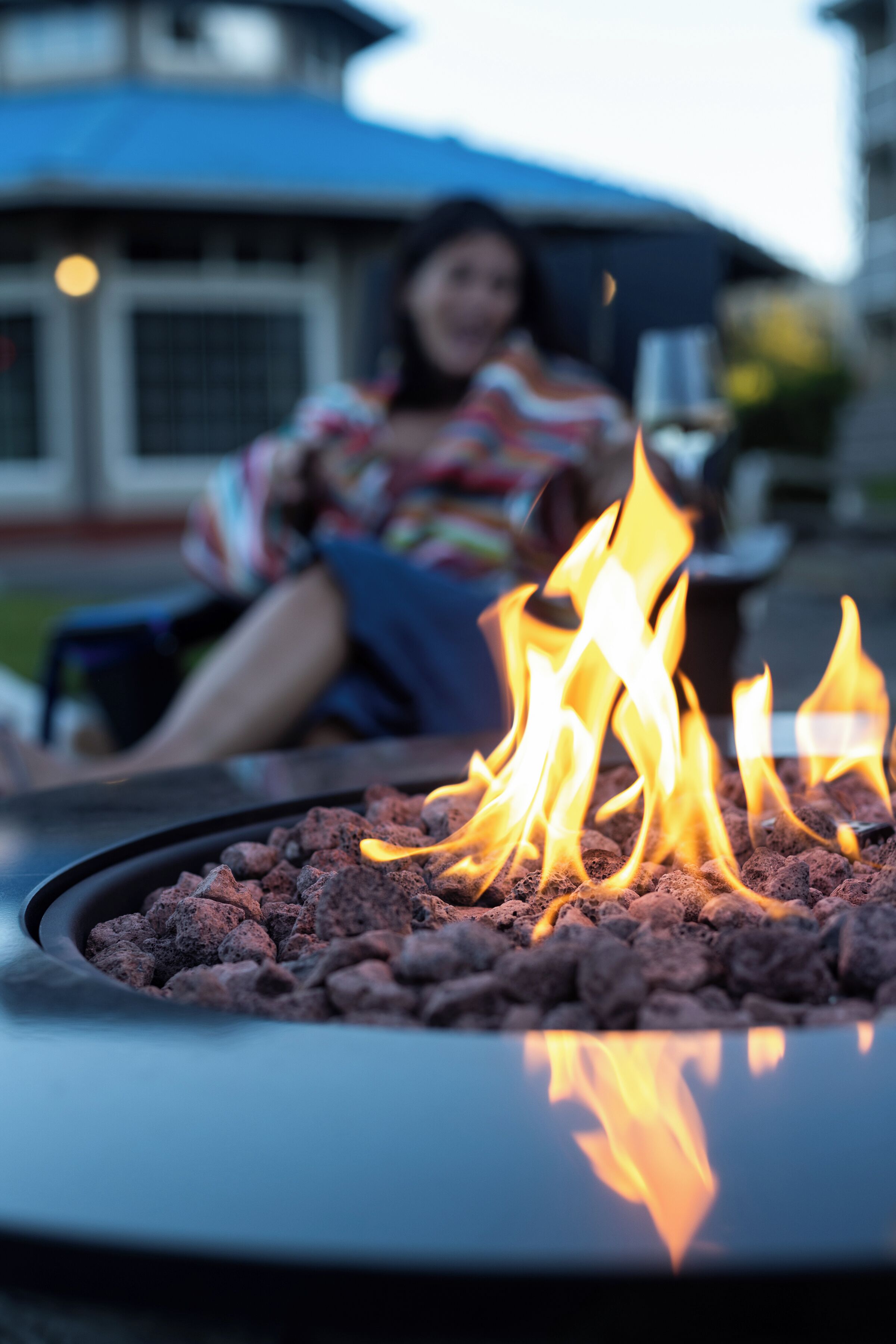 A person sitting by a fire pit with flames.