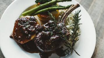 A plate with a lamb chop, asparagus, and a sprig of rosemary.