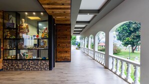 A corridor with a wooden floor, a glass display case with various items, and a view of greenery outside. - Grand Carimã Resort & Convention Center (Foz do Iguaçu)