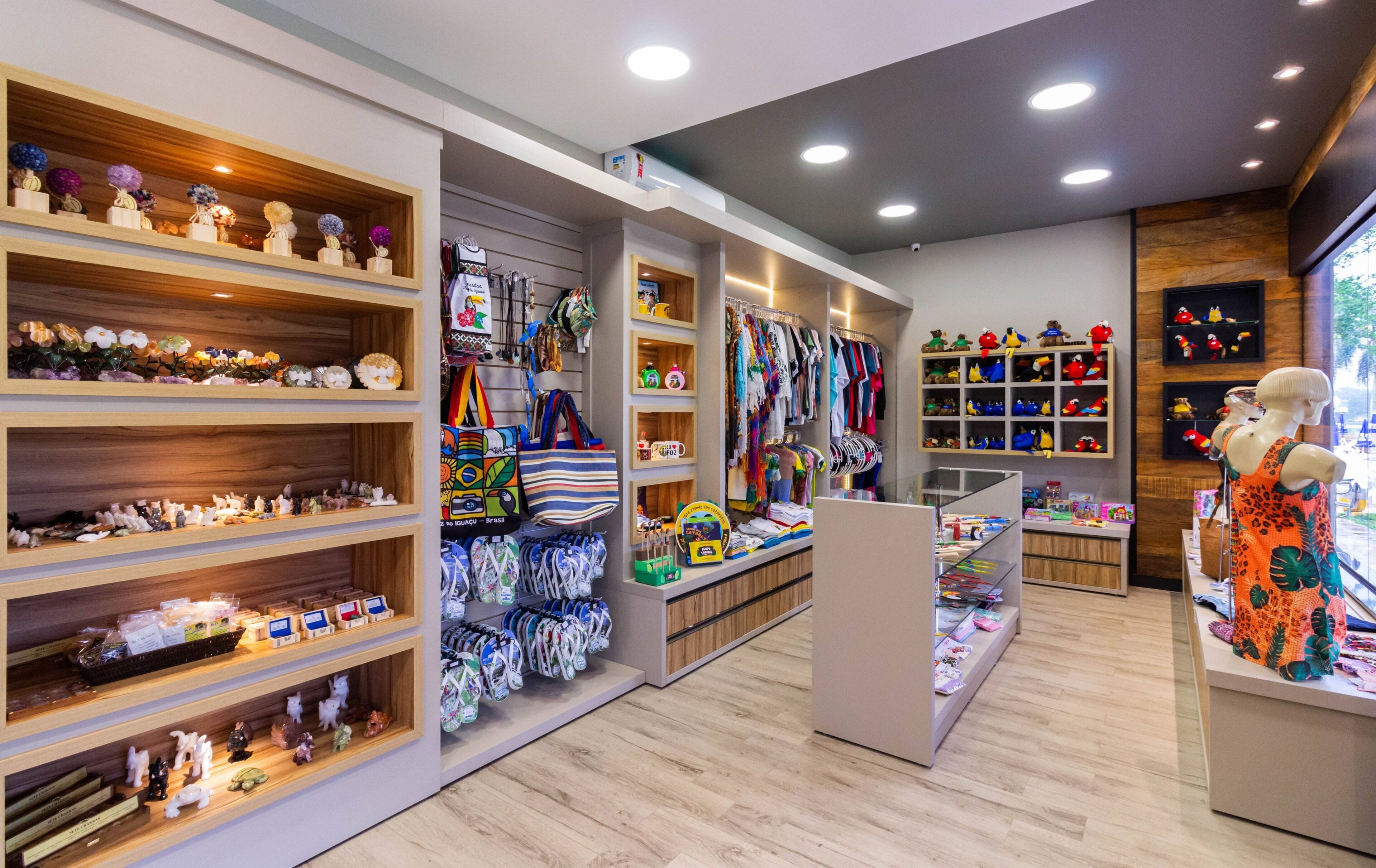 Un magasin de détail avec des étagères en bois où sont exposés divers articles, un mannequin portant une robe colorée et un rayon consacré aux peluches.