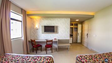 Habitación de hotel con dos camas, un escritorio con silla, televisión y armario.