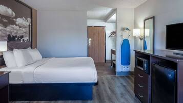 A hotel room with a bed, a dresser, a microwave, a TV, and a large mirror.
