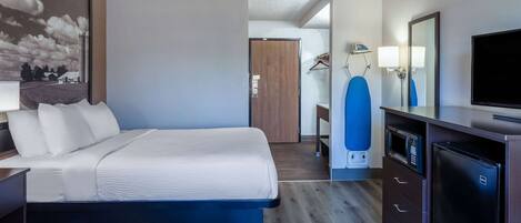A hotel room with a bed, a dresser, a microwave, a TV, and a large mirror.