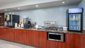 Une cuisine professionnelle équipée d’une machine à café, d’un réfrigérateur, d’un four à micro-ondes et d’un présentoir à pain.