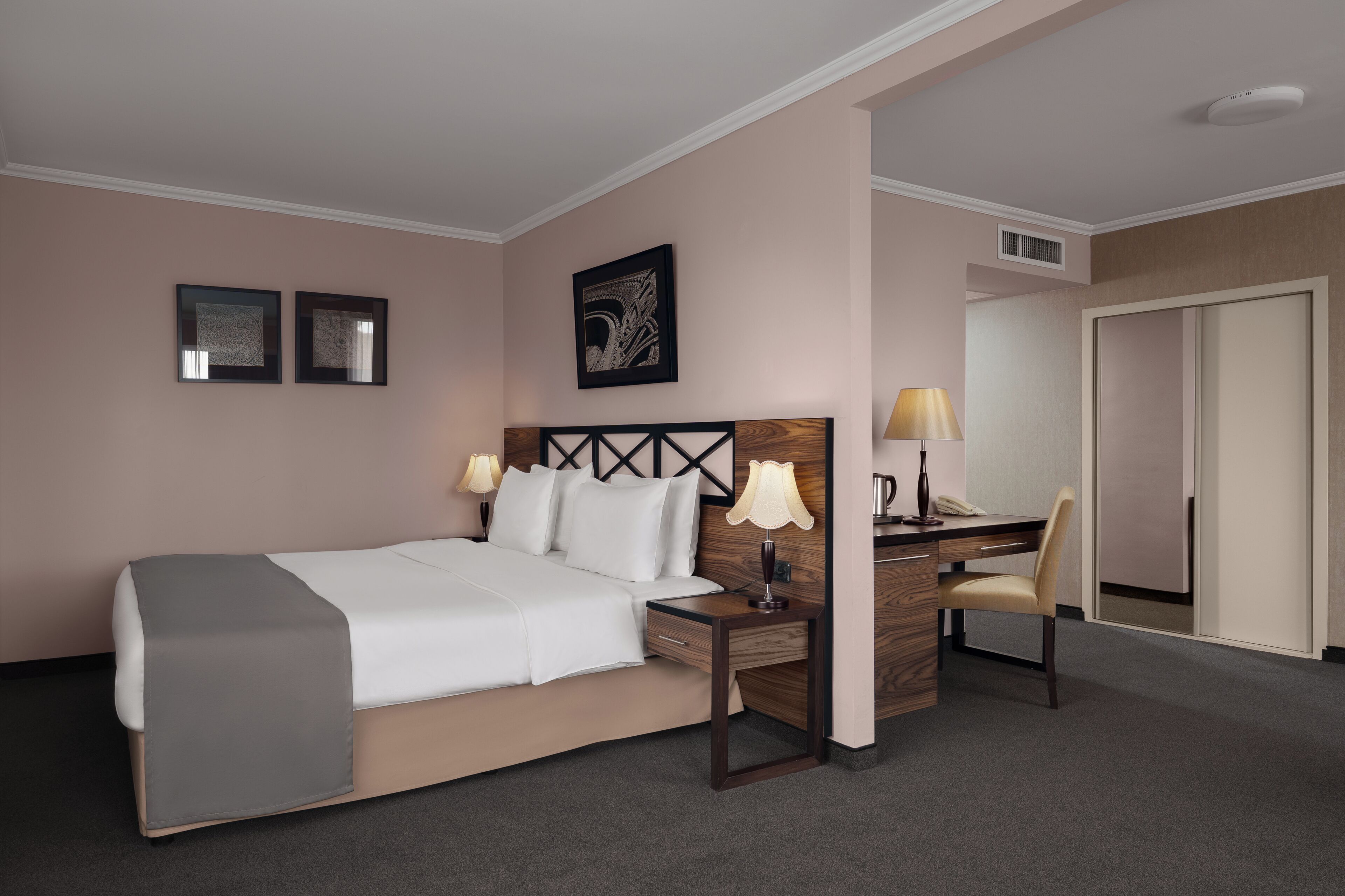Una habitación de hotel con una cama, mesitas de noche, un escritorio y una silla.