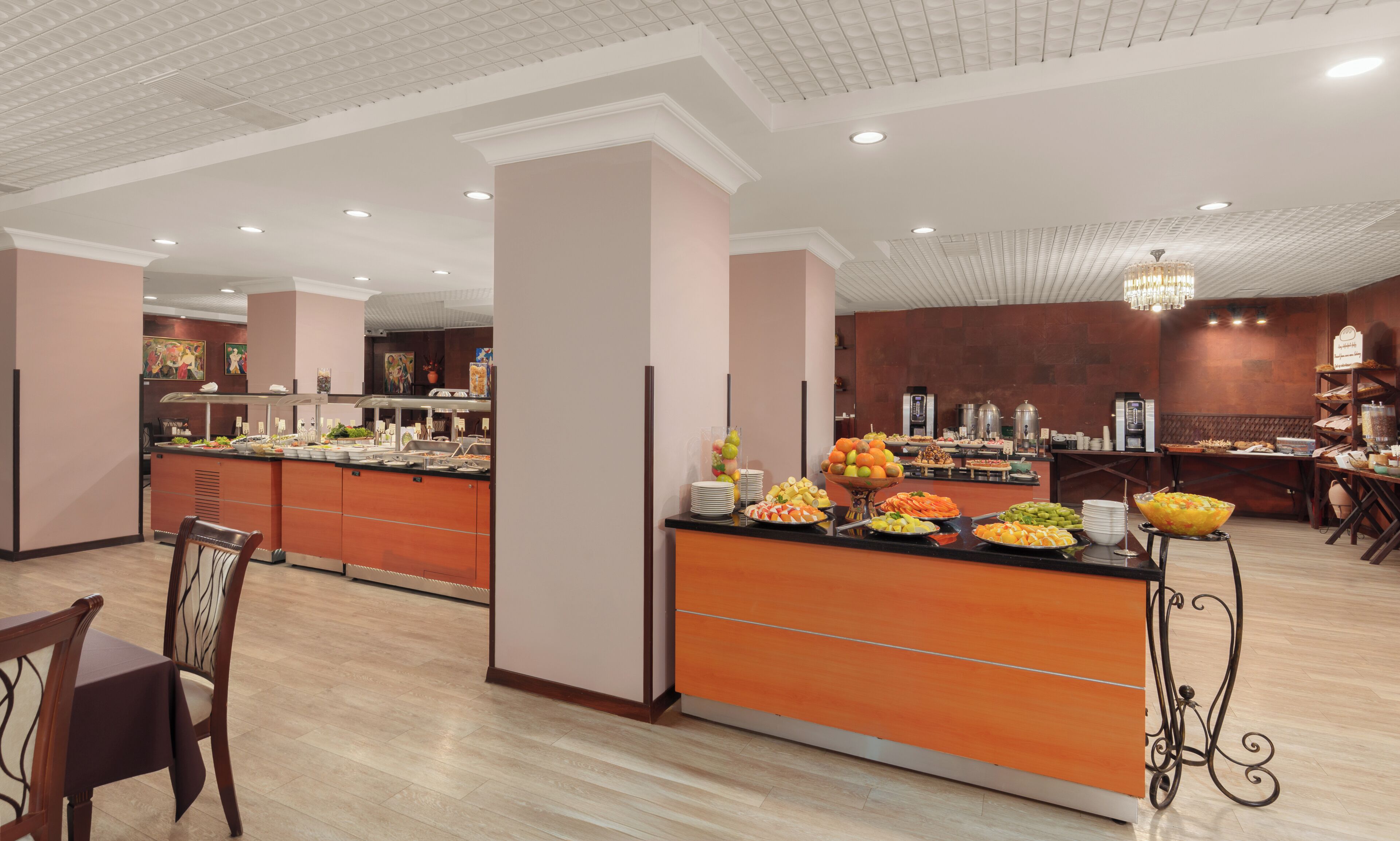 Un área de bufé con diferentes opciones de comida, una estación de café y mesas.