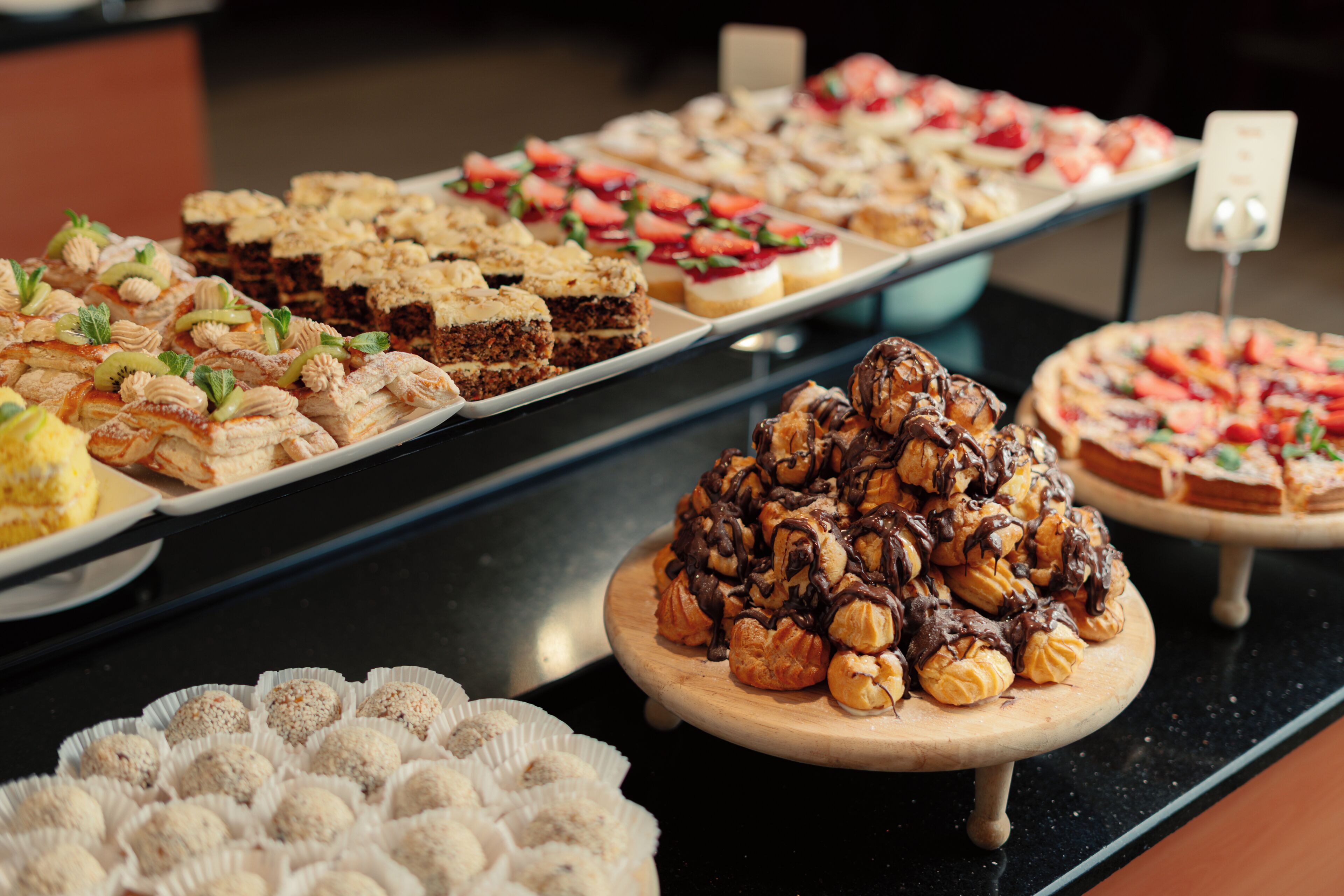 A buffet with various desserts including cakes, pastries, and fruit tarts.