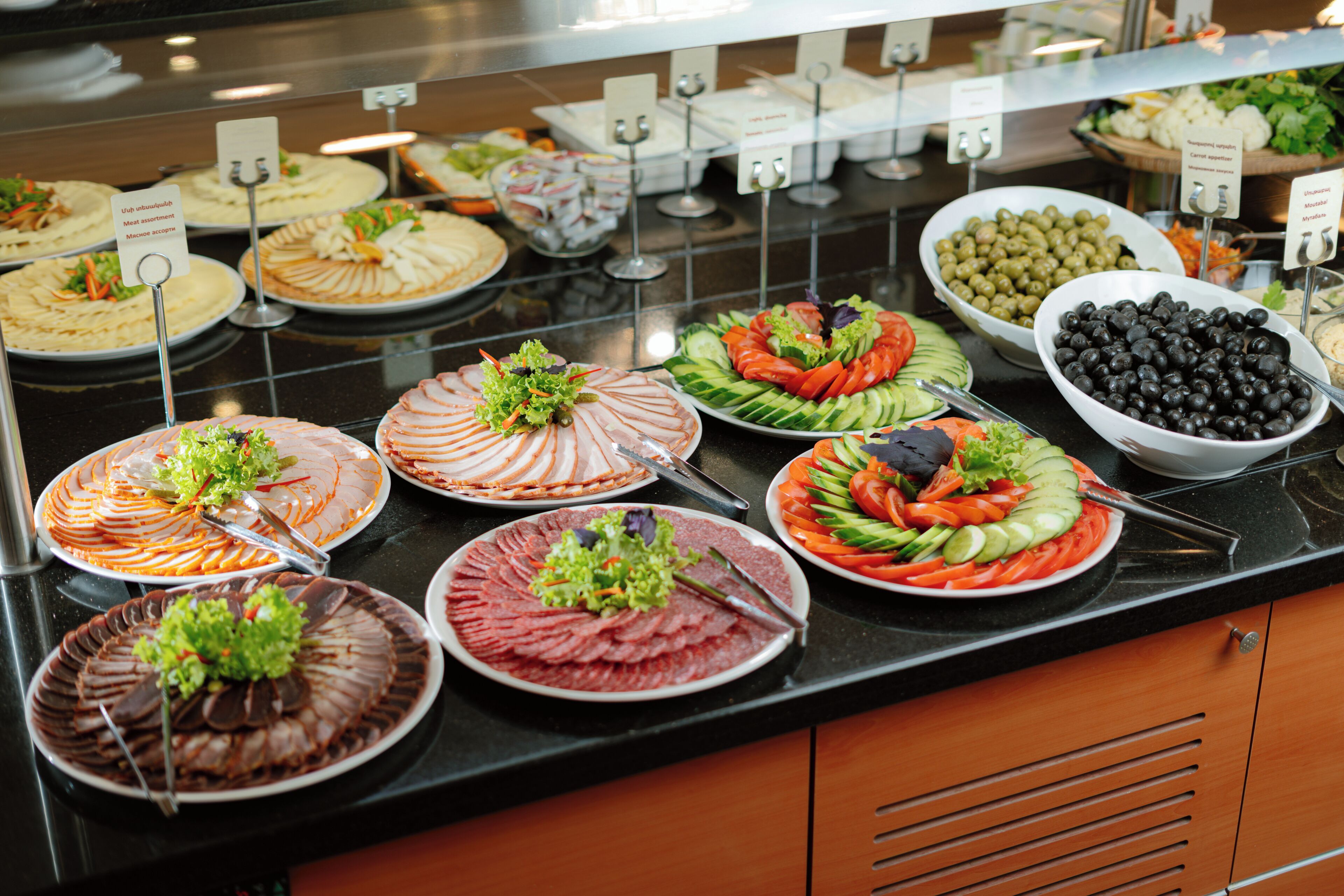 Een buffet met diverse gerechten, waaronder salades, vlees en groenten.