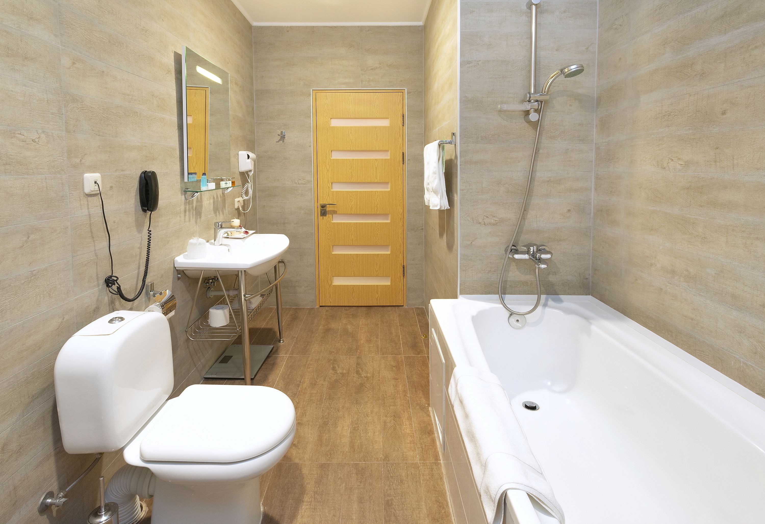 A bathroom with a toilet, sink, mirror, and bathtub.