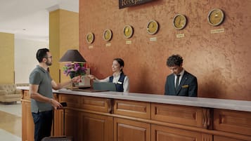 A reception desk with clocks labeled with city names, a sofa, and a lamp with purple flowers.