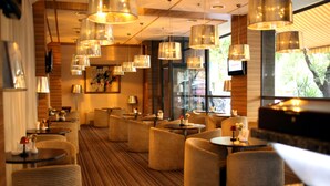 A modern hotel lobby with round seating, pendant lighting, and large windows offering views of greenery. - Ani Plaza Hotel (Yerevan)