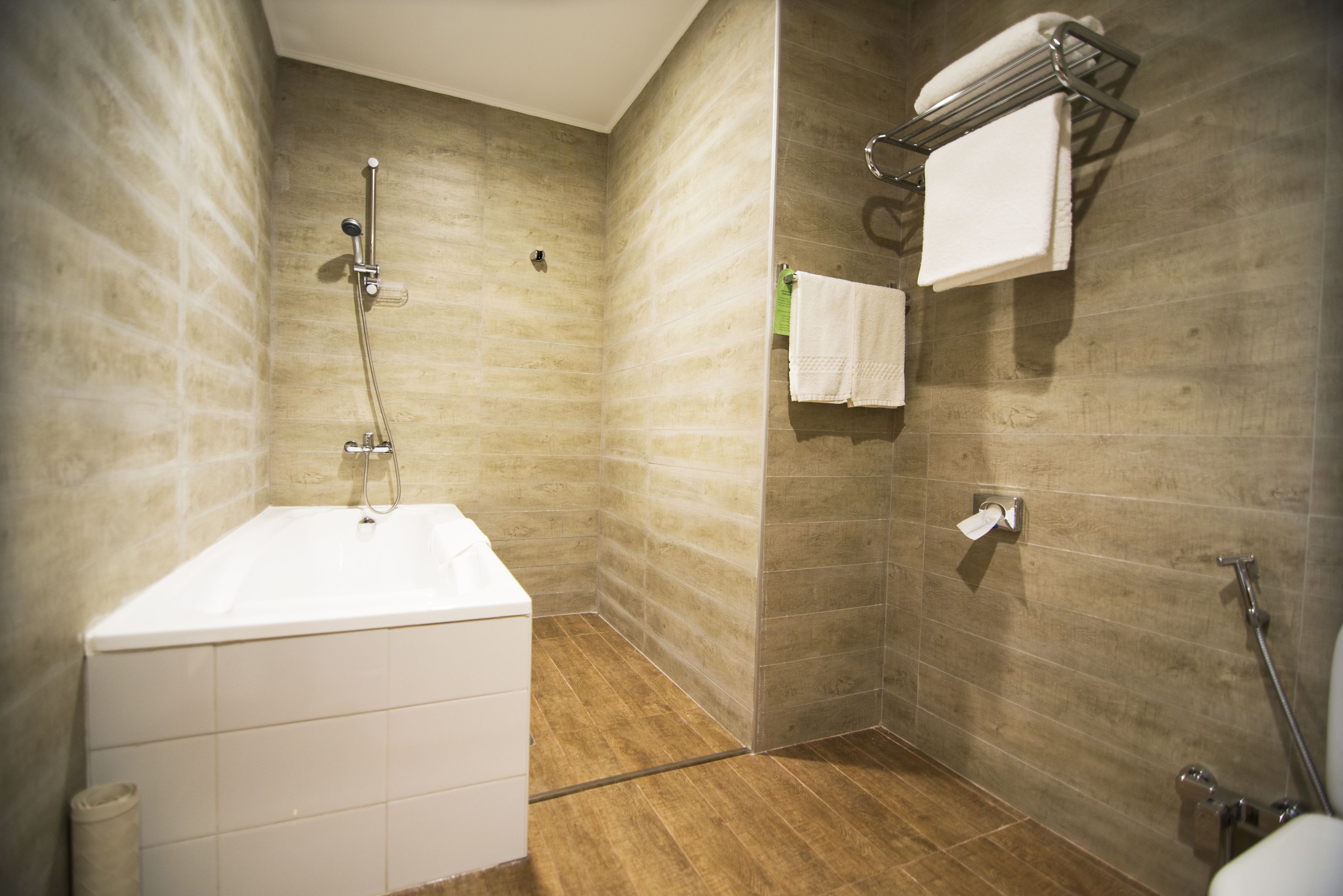 Een moderne badkamer met een bad, douche en handdoekrek.