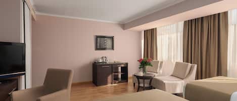 A hotel room with a bed, a desk, a chair, a TV, and a window with curtains.