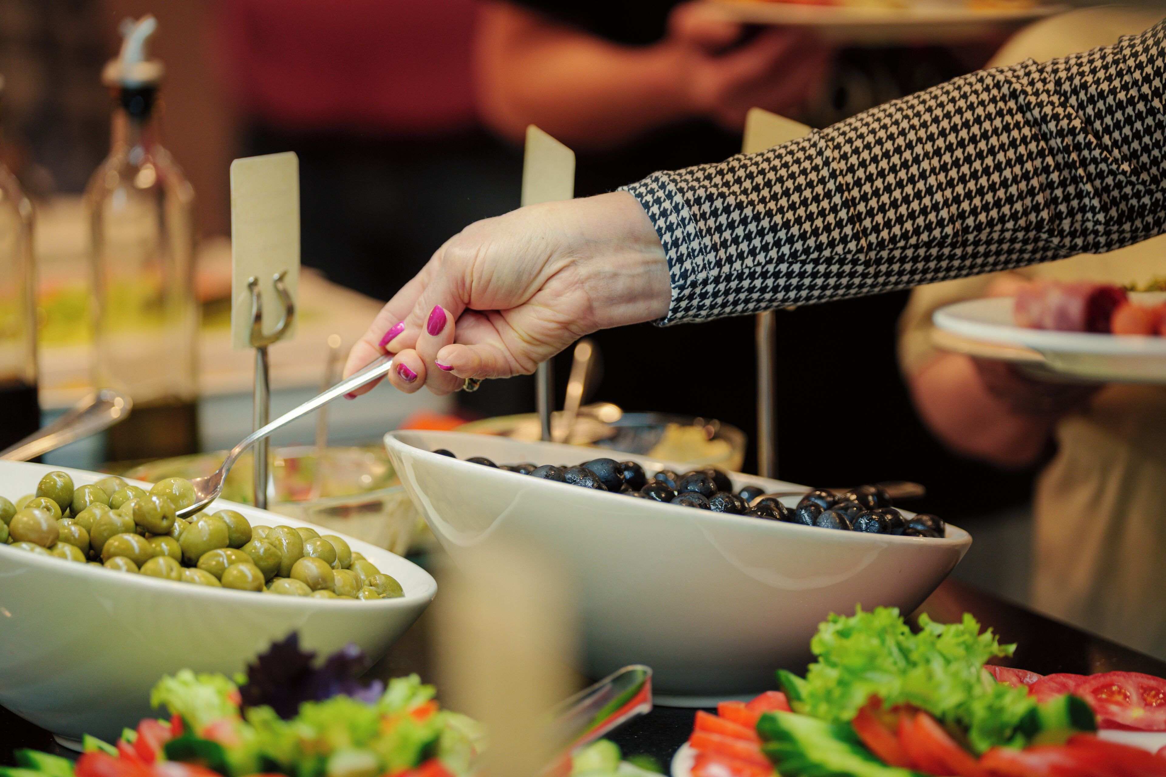 Ein Buffet mit verschiedenen Speisen, darunter Oliven und Salat.