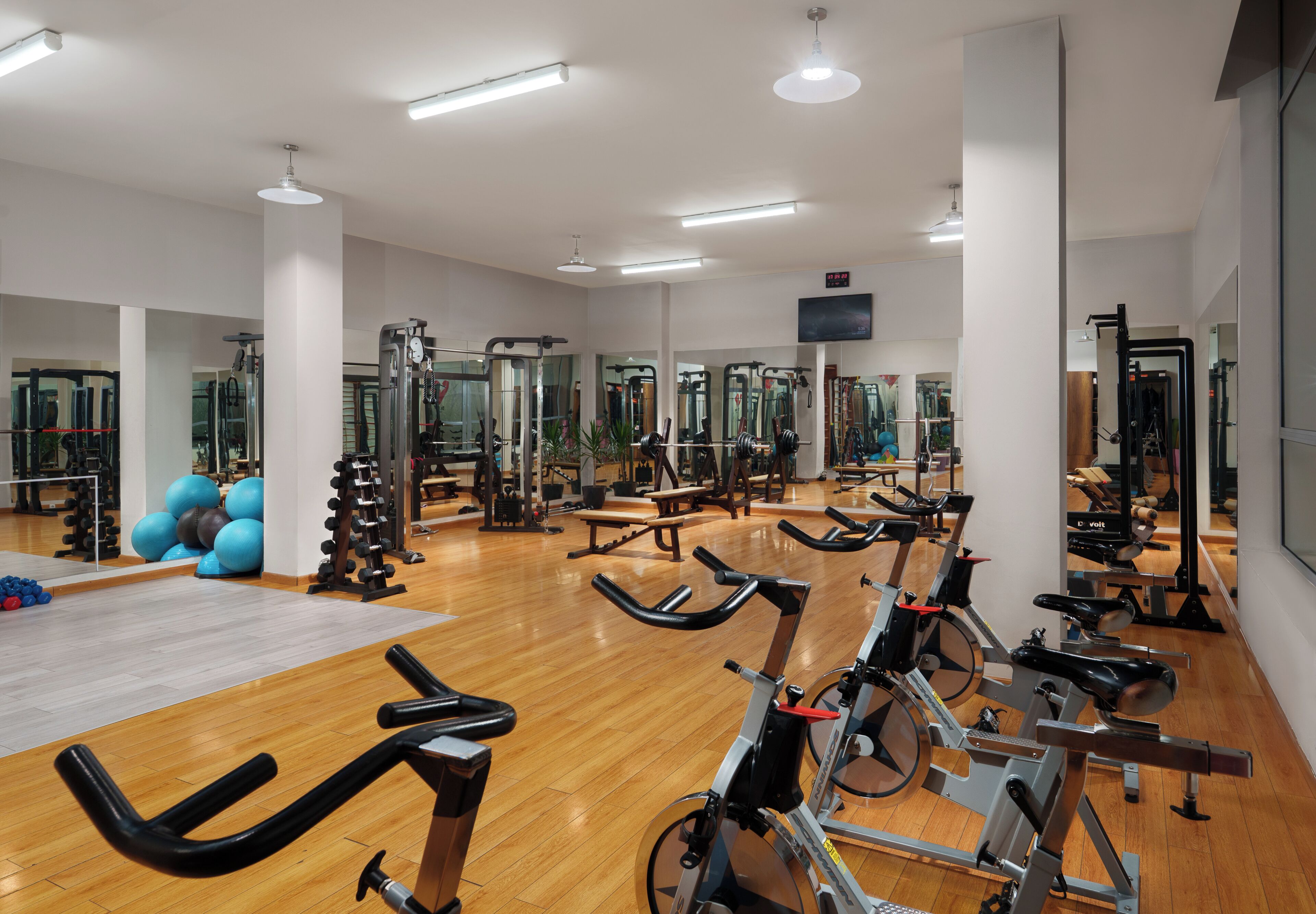 A gym with exercise bikes, a mirrored wall, and weightlifting equipment.
