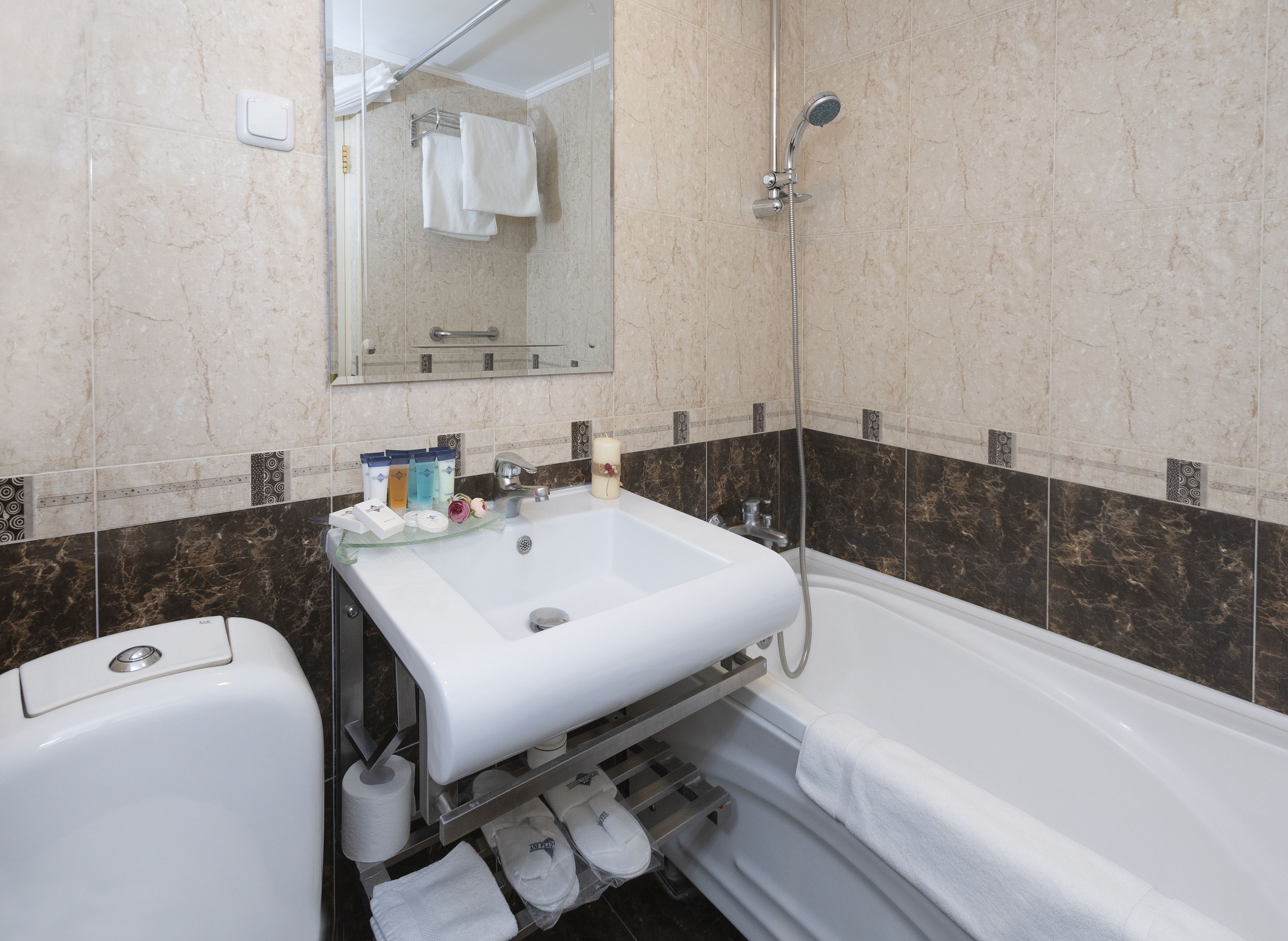 Une salle de bain équipée d’un lavabo, d’un miroir, d’une douche et de toilettes.