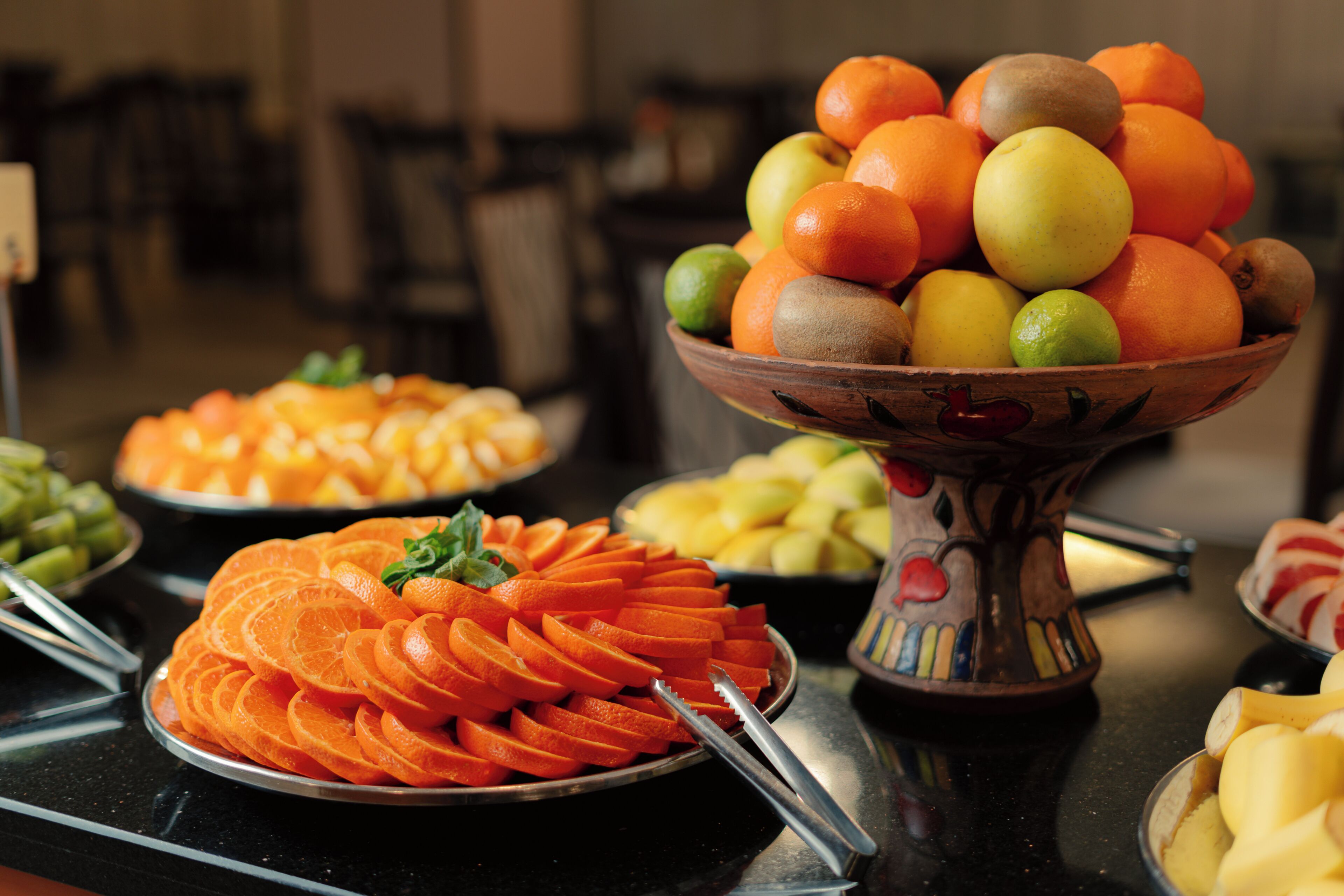 Un bufé con diversas frutas y verduras, como naranjas, kiwis y manzanas.