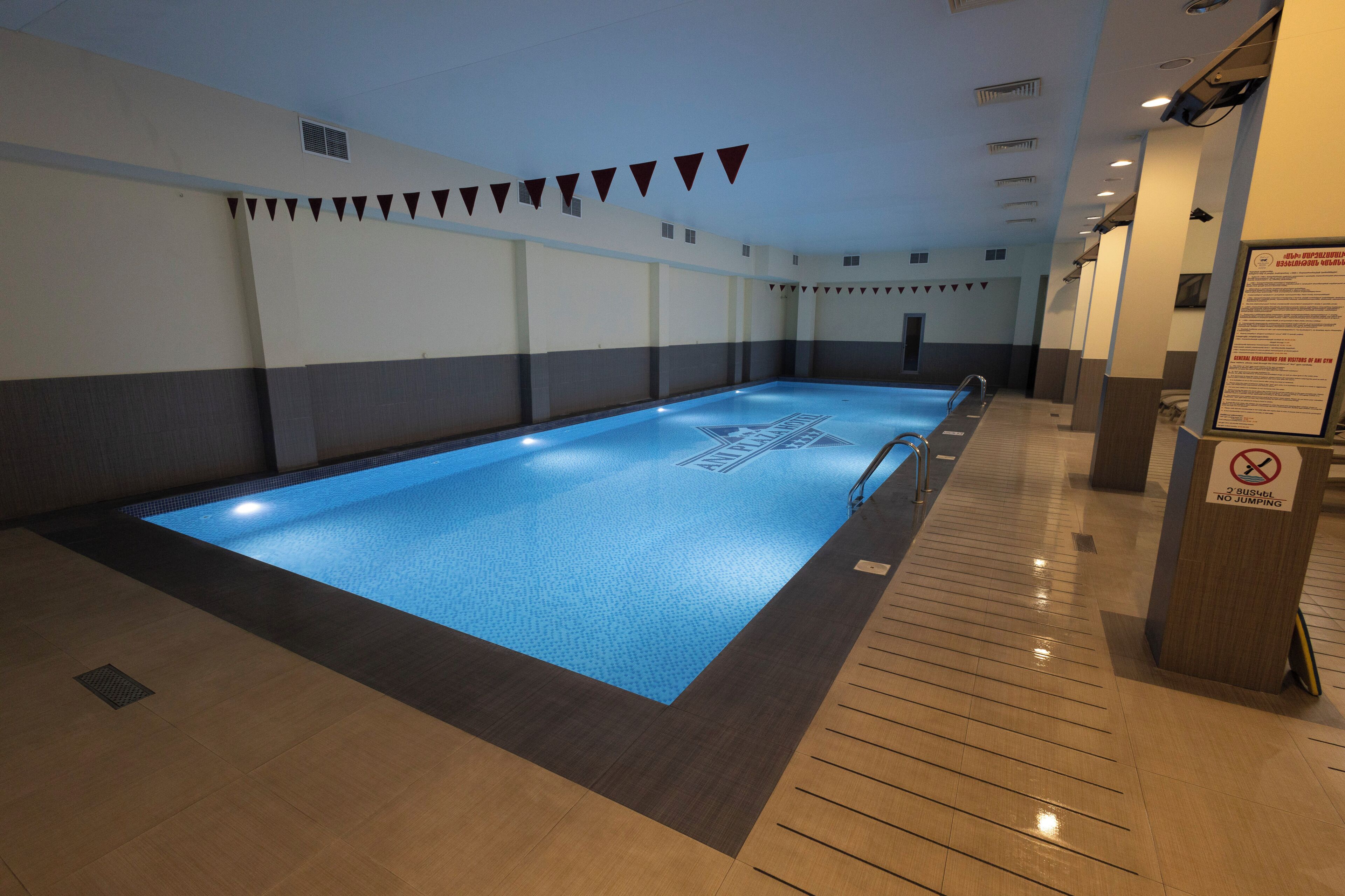 En swimmingpool med ett blått vatten, omgiven av ett kaklat golv och kaklade väggar.