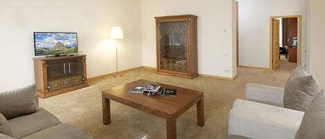A living room with a sofa set, a wooden coffee table, a TV, a lamp, and a cabinet.