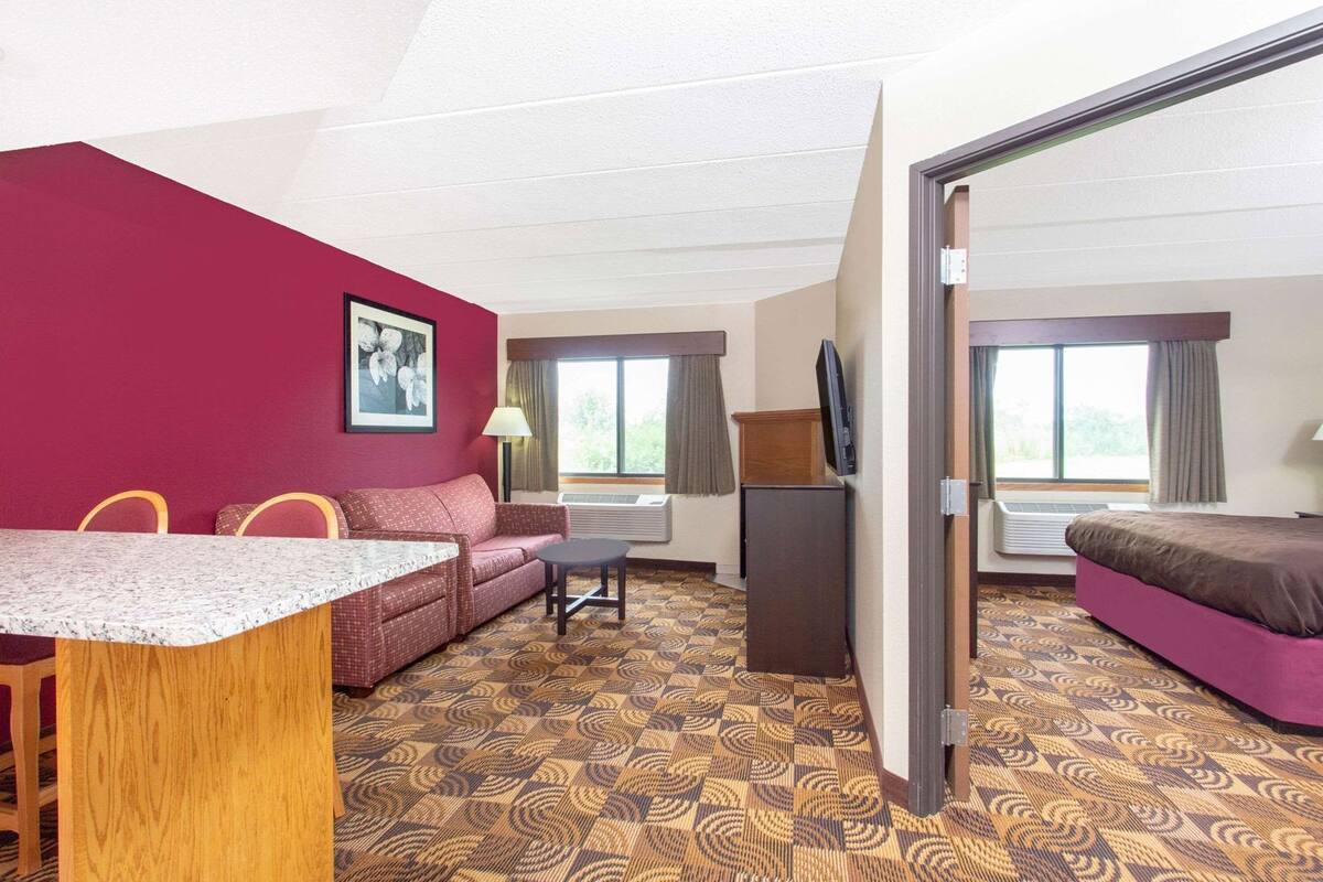 A hotel room with a sofa, a small table, a TV, and a bed.