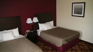 Habitación de hotel con dos camas, una mesita de noche con lámpara y un cuadro enmarcado en la pared.