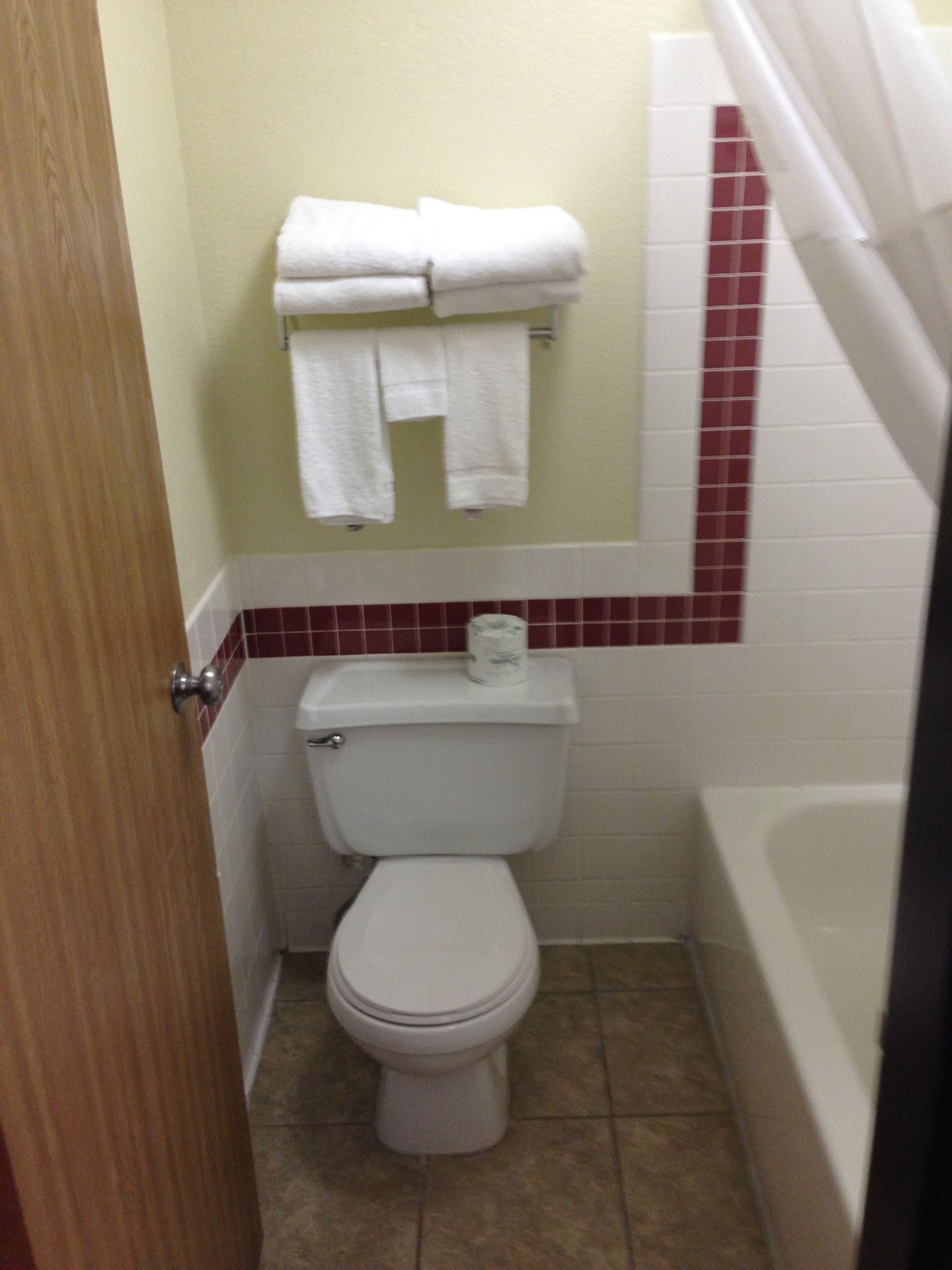 Ein Badezimmer mit Toilette, Handtuchhalter mit gefalteten Handtüchern und einer Badewanne.