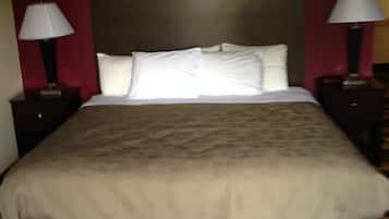 Una habitación de hotel con una cama grande, dos mesitas de noche con lámparas y un cabecero.