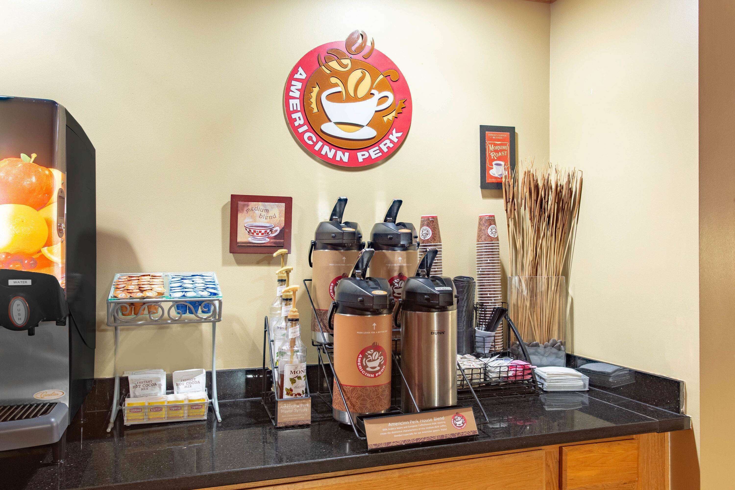 A coffee station with a coffee cup logo, a water dispenser, and various coffee pods and containers.