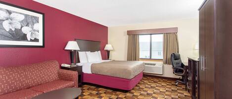 A hotel room with a bed, a sofa, a desk, a chair, and a large window with curtains.