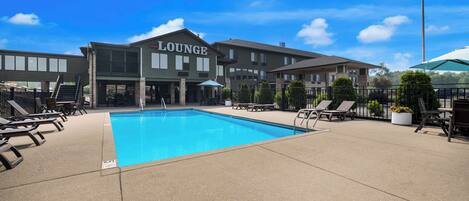 A hotel with a swimming pool, lounge area, and outdoor seating.
