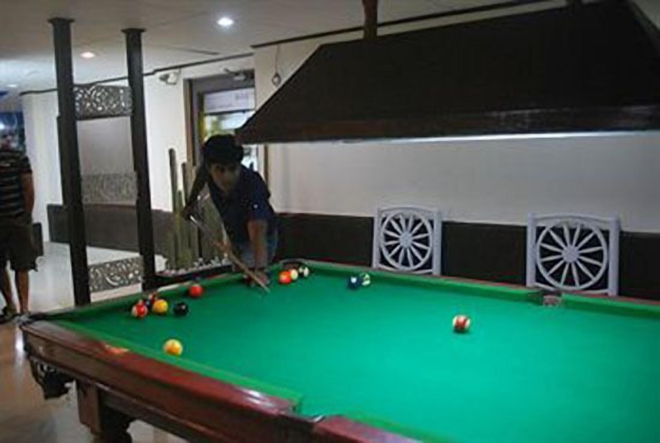A pool table with balls and a person playing.