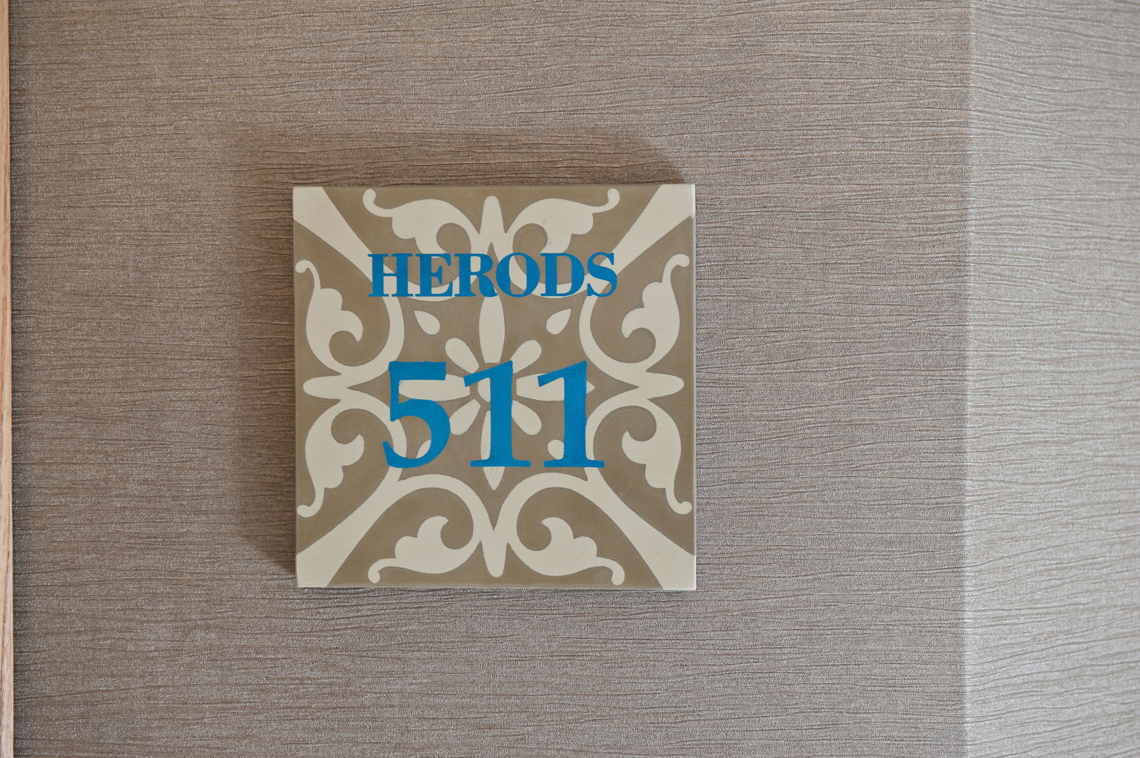 A framed sign with the text "HERODS 511" on a textured wall.