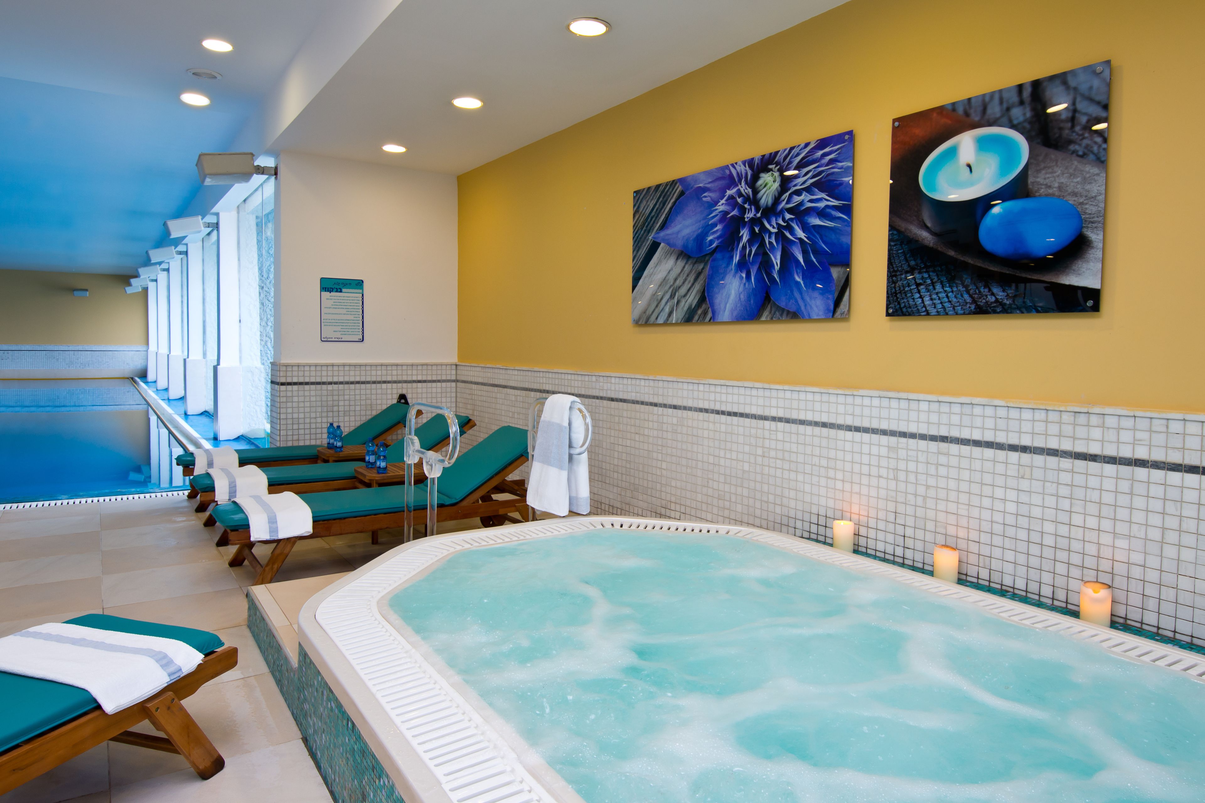 Uma área de spa com uma grande banheira de hidromassagem, espreguiçadeiras e obras de arte fixadas na parede.