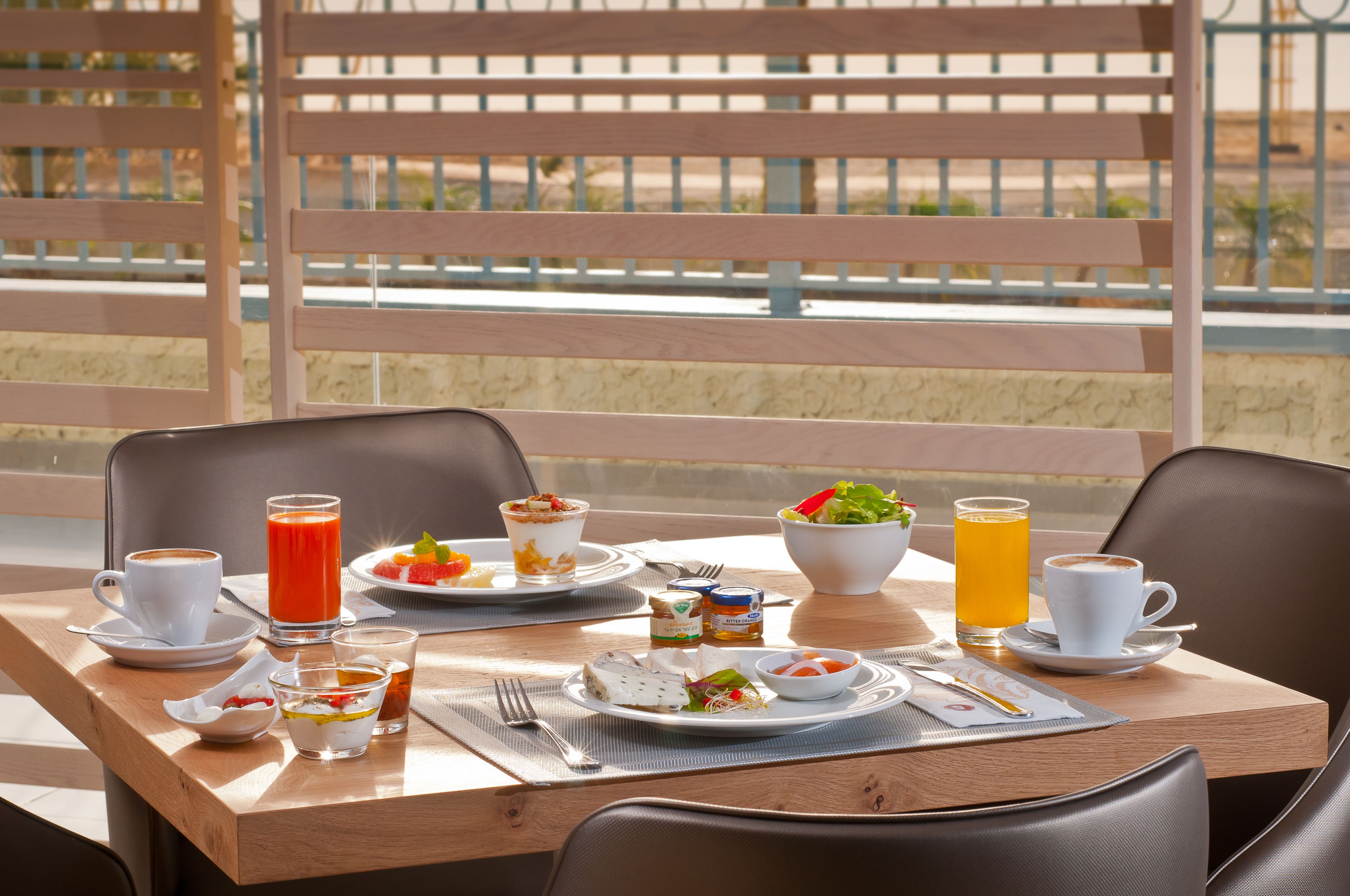 A breakfast table with plates of food, cups of coffee, and glasses of juice.