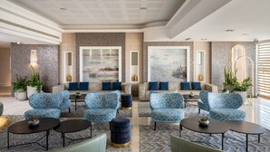 Een moderne lobby met gestreepte banken, ronde tafels en potplanten.