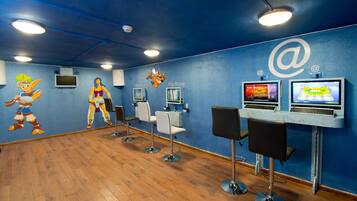 Habitación con pared azul, piso de madera y dos estaciones de juego PlayStation.